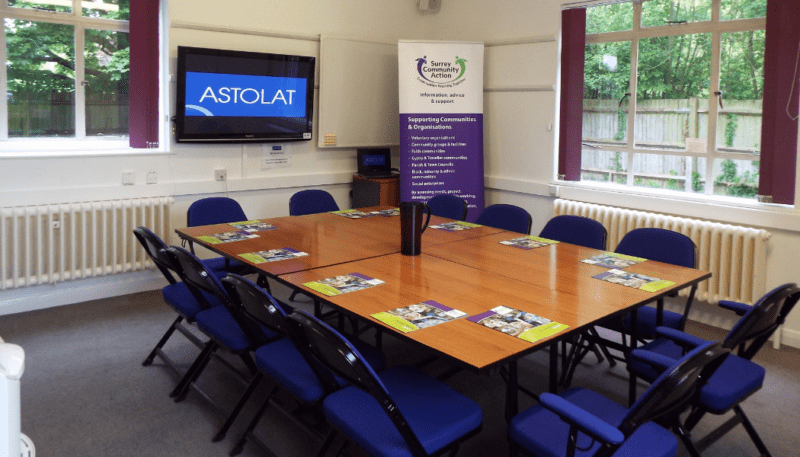 A meeting room with the surrey community action banner in the background.