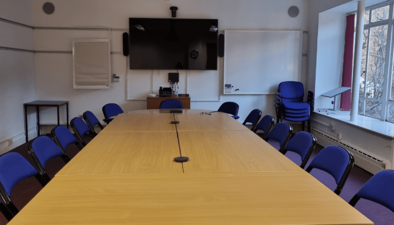 Meeting Room with empty chairs, table and a large sized screen.